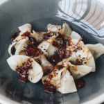 Pork and garlic chive dumplings with dry chilli and Sichuan pepper sauce